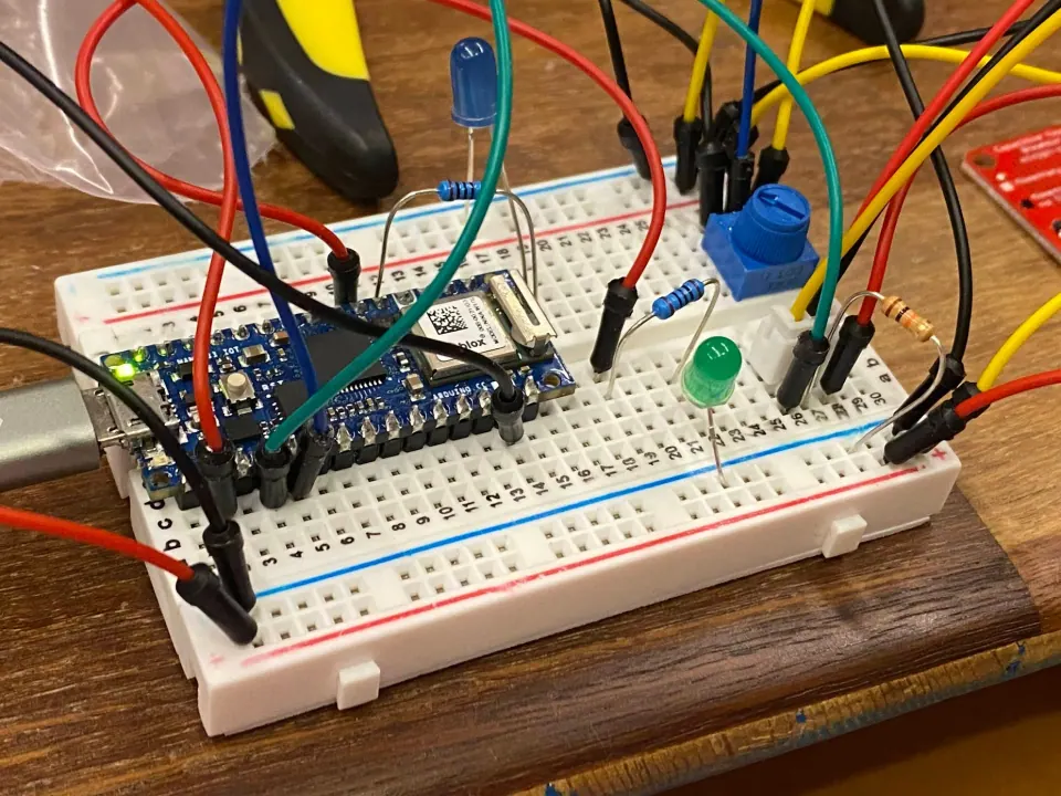 Breadboard with an Arduino Nano 33 IoT, a blue trim pot and blue and green LEDs, wired with jumper wires
