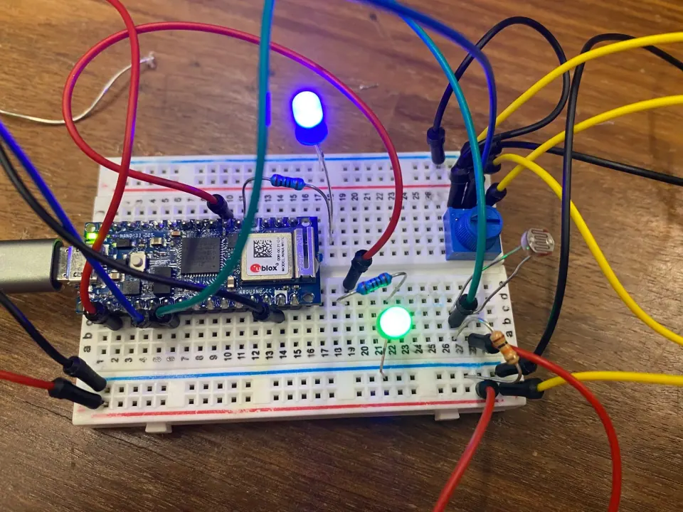 The same breadboard with a photoresistor in place of the touch sensor and the blue and green LEDs lit
