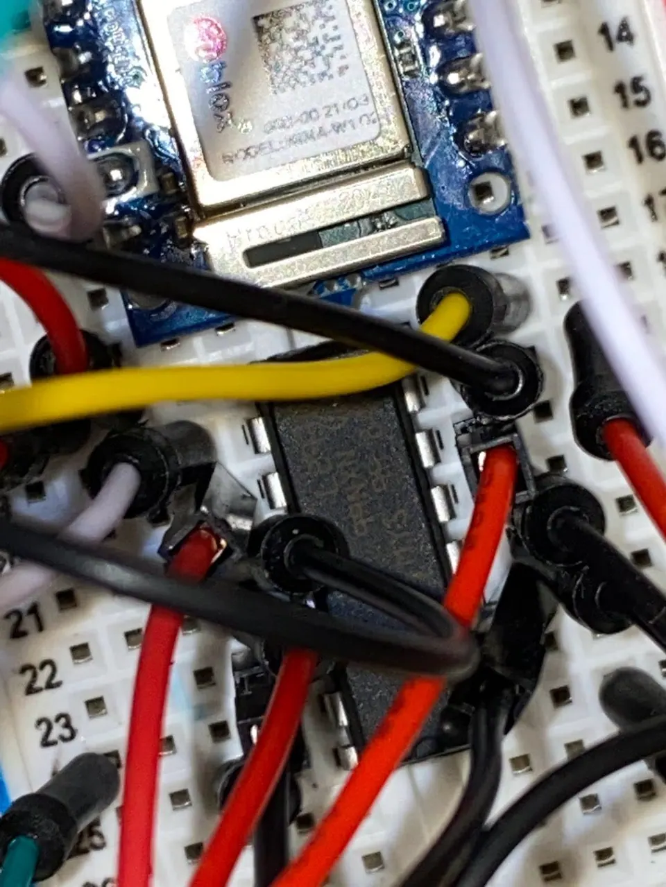 Close-up of an L293D chip on a breadboard, surrounded by jumper wires, beside an Arduino Nano 33 IoT