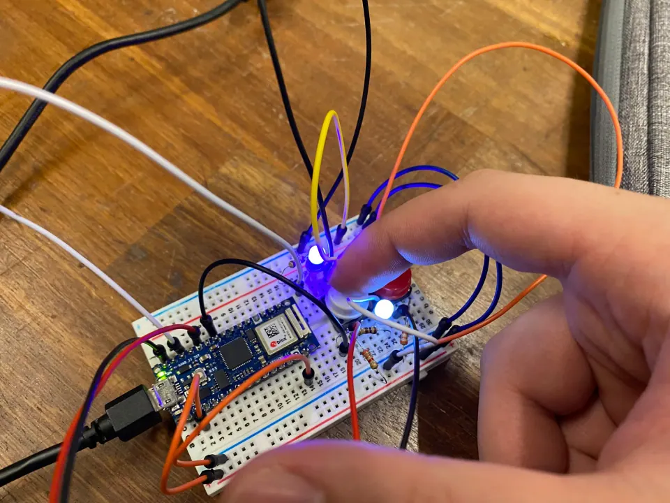 A hand pressing both buttons at once, with the blue and white LEDs both lit