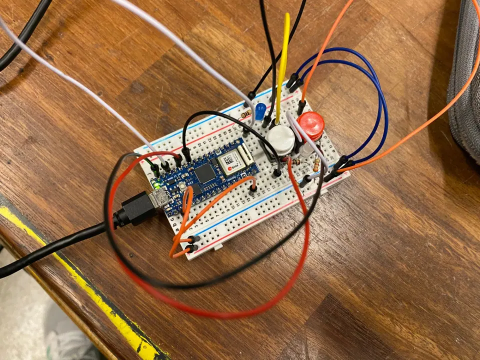 Breadboard with the Arduino, two pushbuttons and two LEDs wired with orange, blue, black and white jumpers