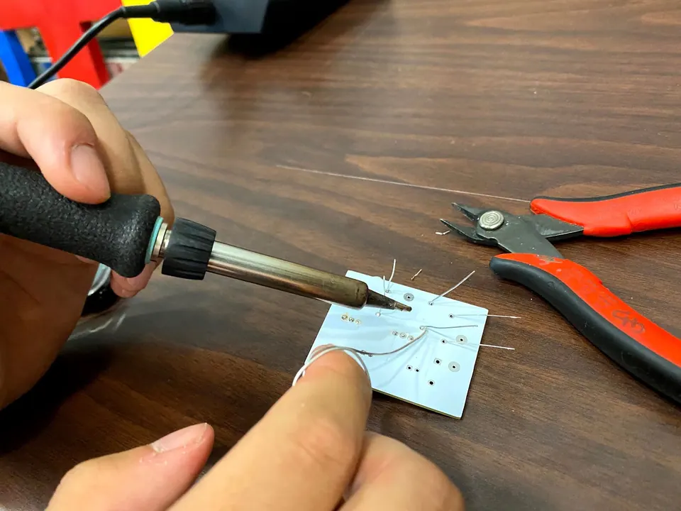A soldering iron touching the logic probe circuit board, with wire cutters nearby