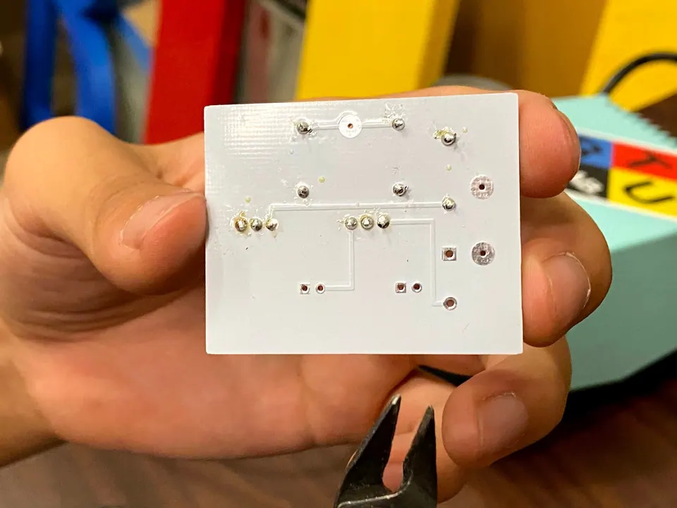Back of the circuit board showing soldered joints and traces, held in a hand