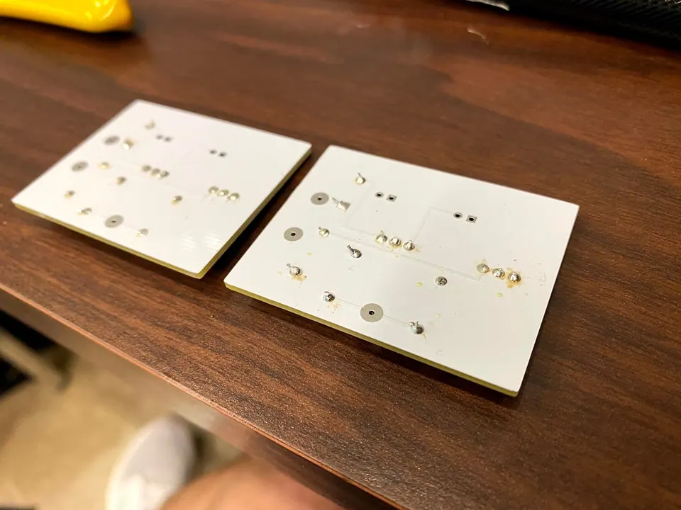 Two circuit boards at an angle on a table, showing their solder joints