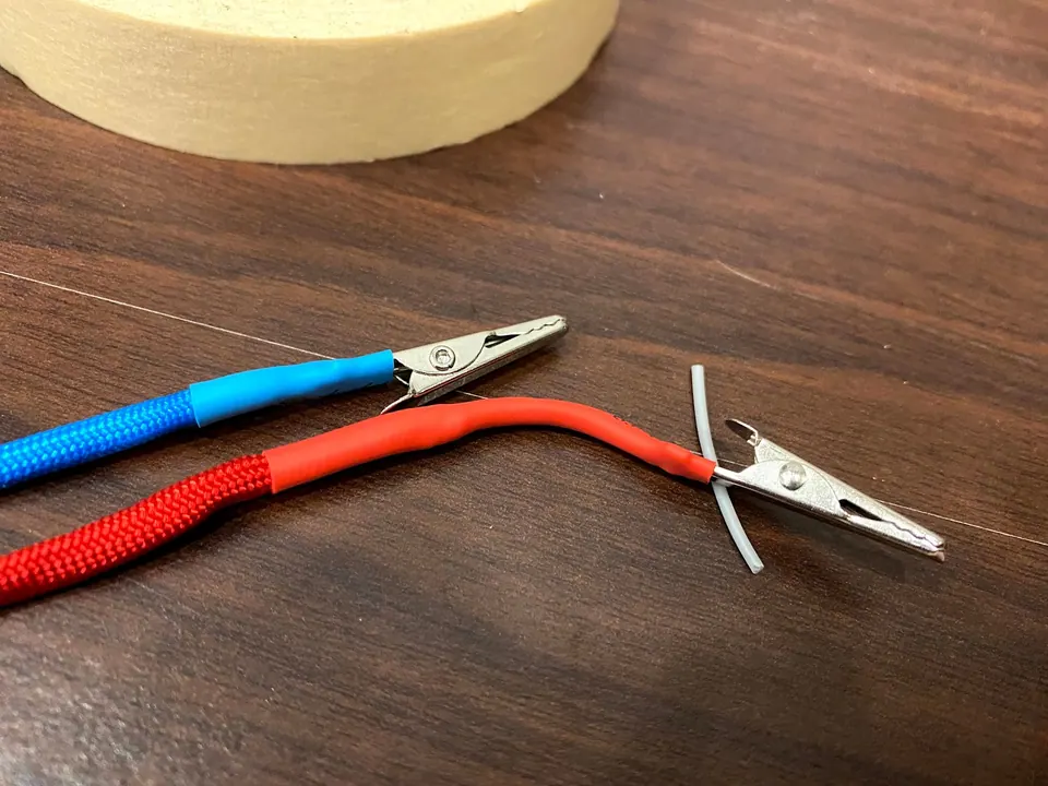 Blue and red cords with alligator clips attached and covered in matching heat shrink