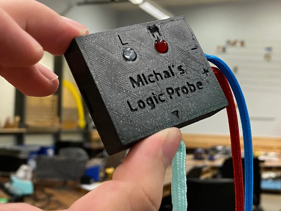 Hand holding the finished logic probe, showing the engraved name and fitted LEDs