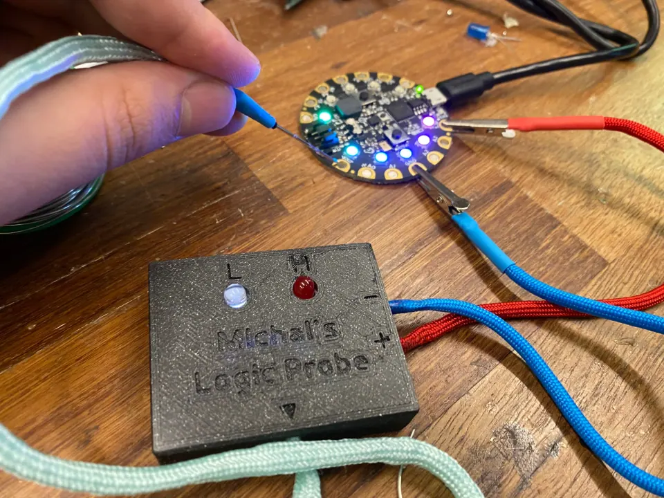 Needle probe touching the Circuit Playground board while the probe’s white L LED glows