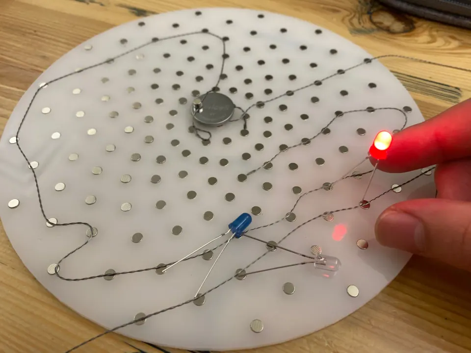 ThreadBoard with the red LED lit while a hand touches the thread