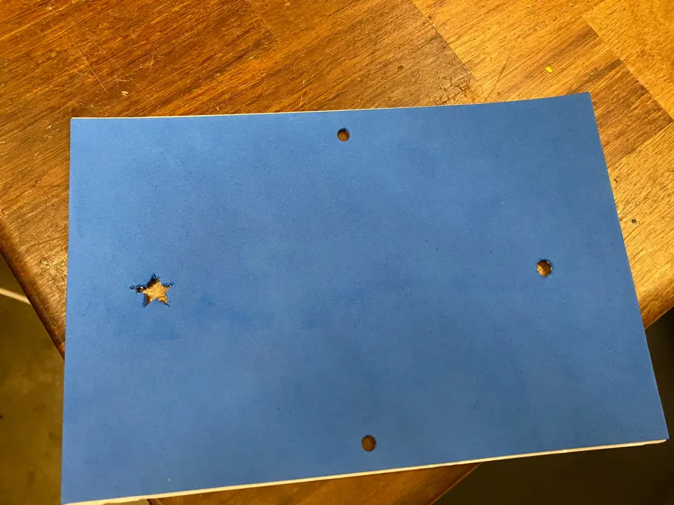 Blue foam sheet with a star cut-out, a punched hole on the right and holes at the top and bottom