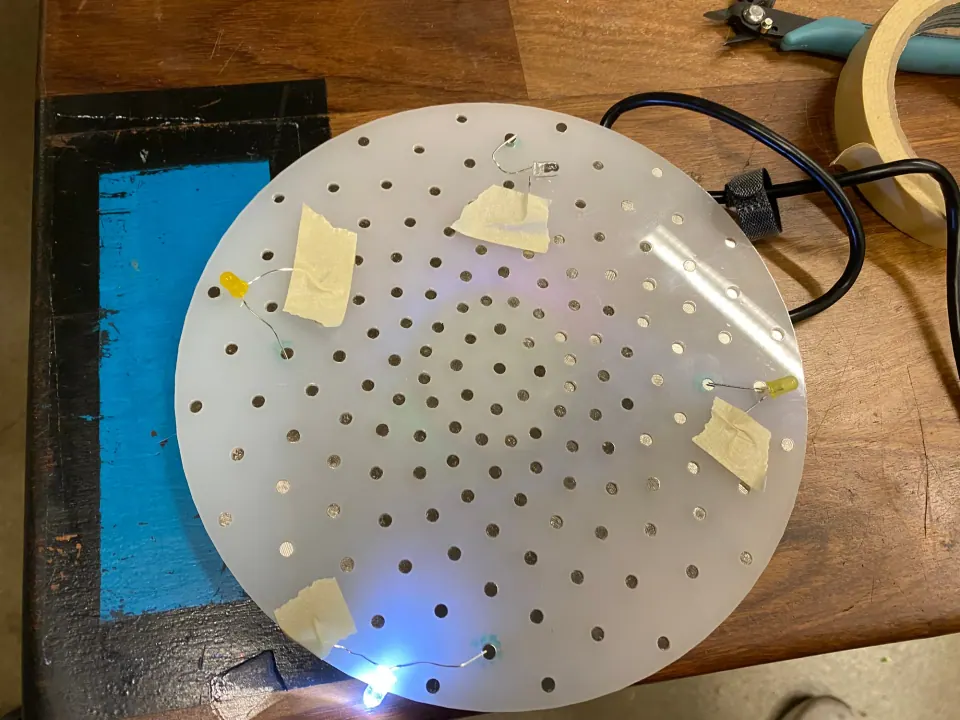 ThreadBoard with yellow and blue LEDs taped to the edge of the disc, one of them lit