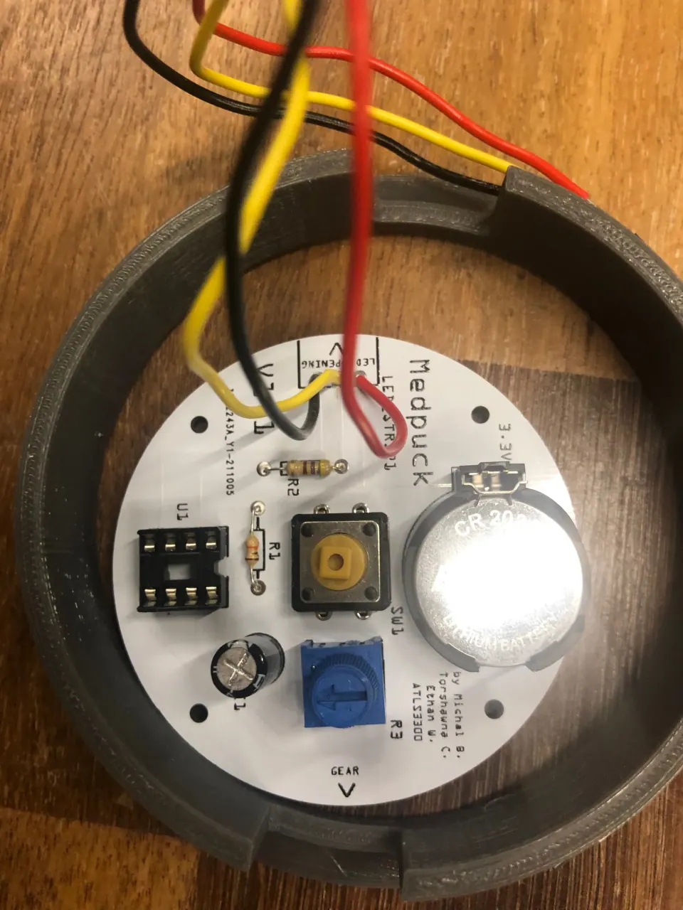 Soldered PCB with the coin cell fitted, seated in the grey printed ring with wires coming off the top